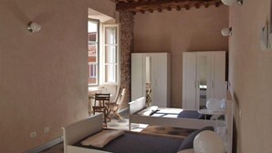 A bedroom with a bed, a chair, a desk, and a wardrobe. - Ostello Palazzo Nizza (Massa)