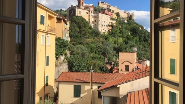 A view of a hillside town with buildings, some with red-tiled roofs, and greenery. - Ostello Palazzo Nizza (Massa)