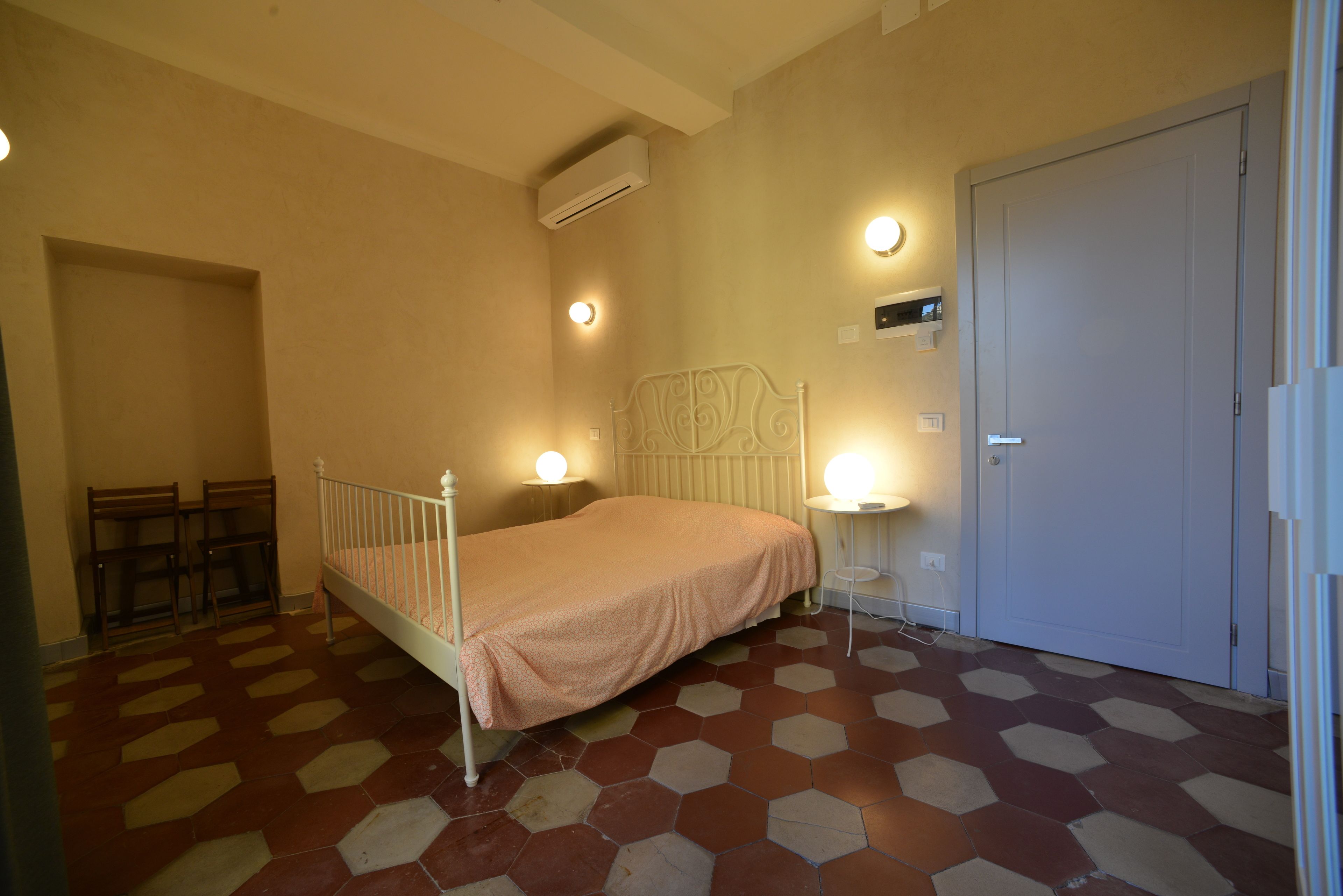 A bedroom with a bed, bedside tables, a wardrobe, and a radiator.