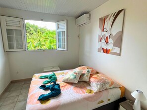 Une chambre à coucher avec un lit, une fenêtre, un climatiseur fixé au mur et un tableau.
