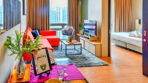 A modern hotel room with a red sofa, a small coffee table, a TV, and a bed. - Swiss Garden Apex Suites Bukit Bintang (Kuala Lumpur)