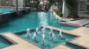 A swimming pool with multiple water jets and surrounding stone structures.