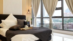 A modern bedroom with a large bed, a city view, and a small table with a tray. - Swiss Garden Apex Suites Bukit Bintang (Kuala Lumpur)