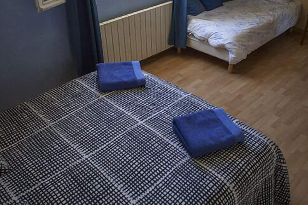 A bedroom with a large bed, a smaller bed, and a window with curtains.