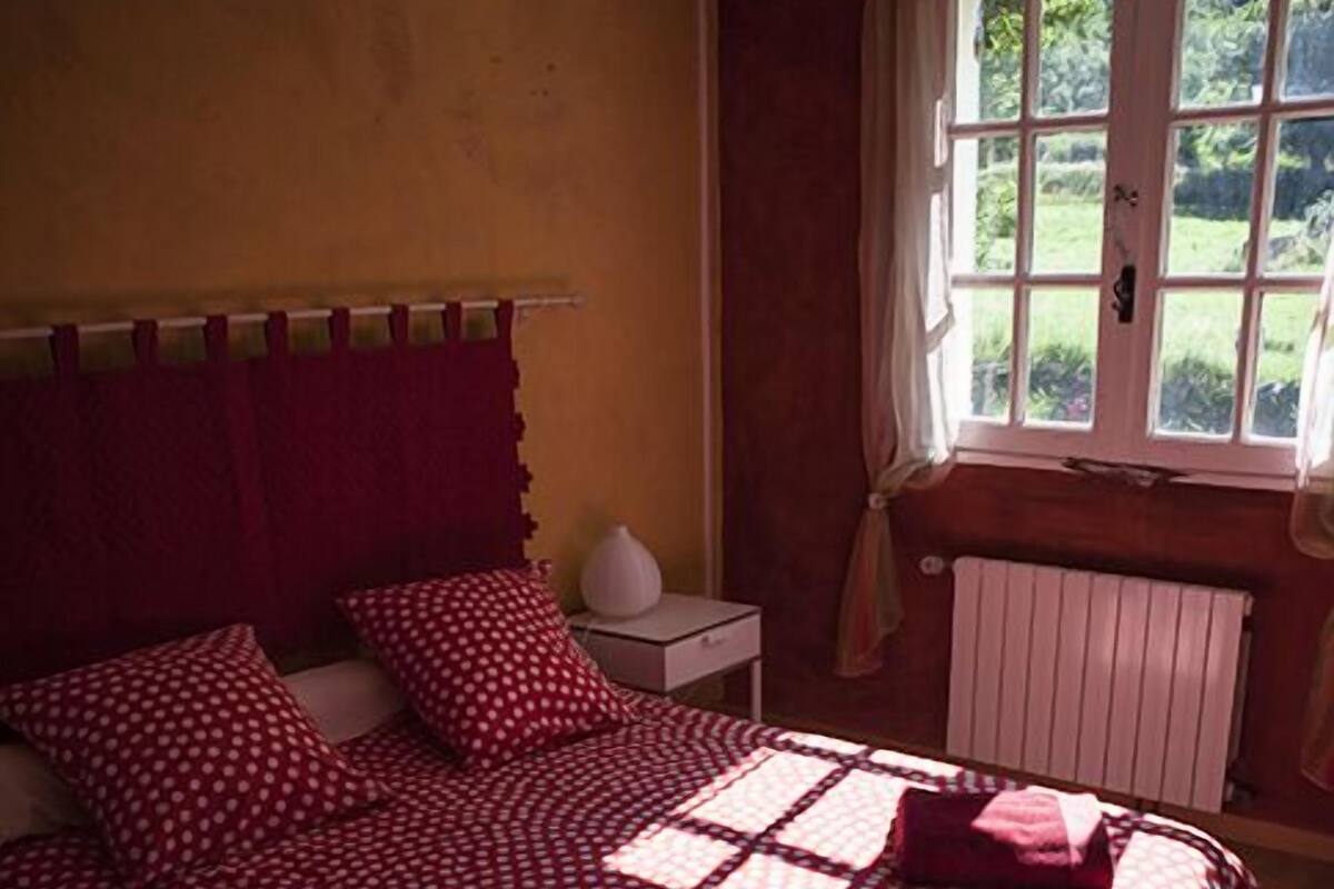 A bedroom with a bed, a window, and a radiator.