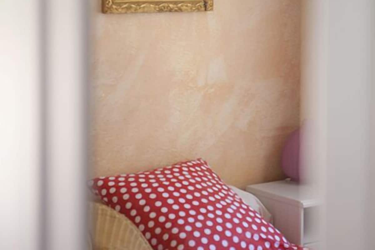 A bedroom with a bed, a pillow, a nightstand, and a framed picture on the wall.