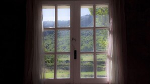 A room with a large window offering a view of a green landscape. - Auberge De La Vallée (Saint-Jean-de-Bueges)