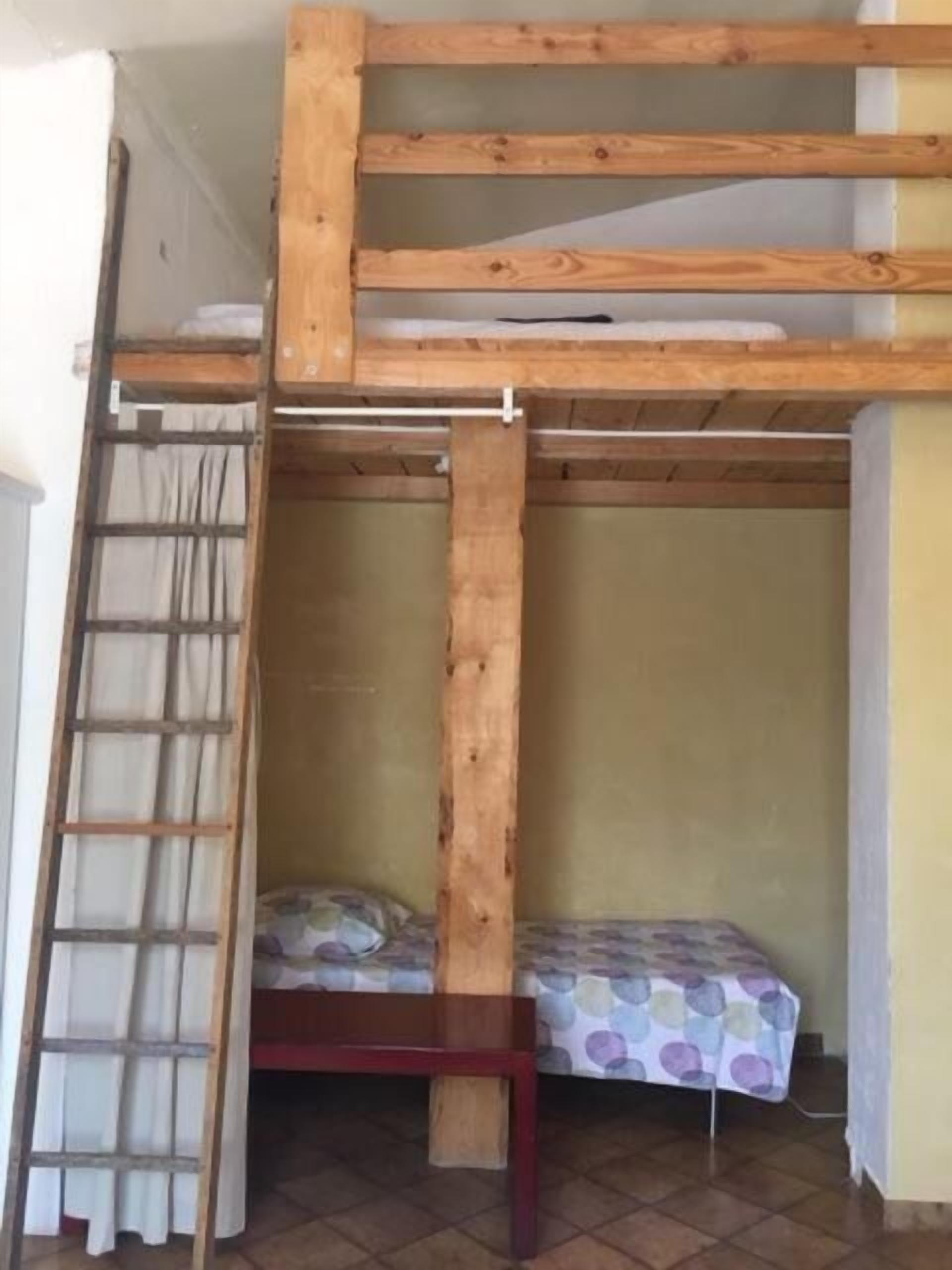 Habitación con literas, una mesita y una colcha estampada.