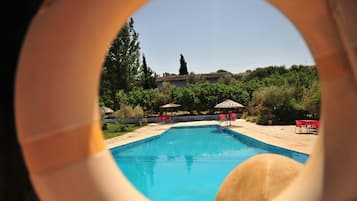 Una piscina al aire libre de temporada, sombrillas, tumbonas