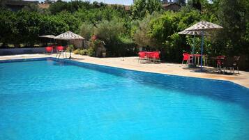 Una piscina al aire libre de temporada, sombrillas