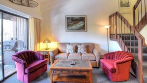 A living room with a sofa, two armchairs, a coffee table, a lamp, and a painting on the wall. - (A211) Loft Condominiums (Yosemite National Park)