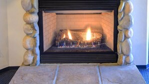 A stone fireplace with a wooden mantel and a framed landscape painting above it. - (A211) Loft Condominiums (Yosemite National Park)