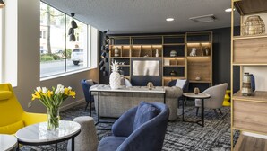 A modern lounge area with seating, a coffee table, and a decorative vase with flowers. - Appart'hôtel Odalys City - Le Mans Centre Palais des Congrès (Le Mans)