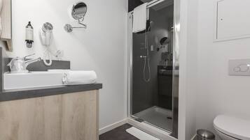 A modern bathroom with a glass-enclosed shower, a white sink with a towel, and a mirror.