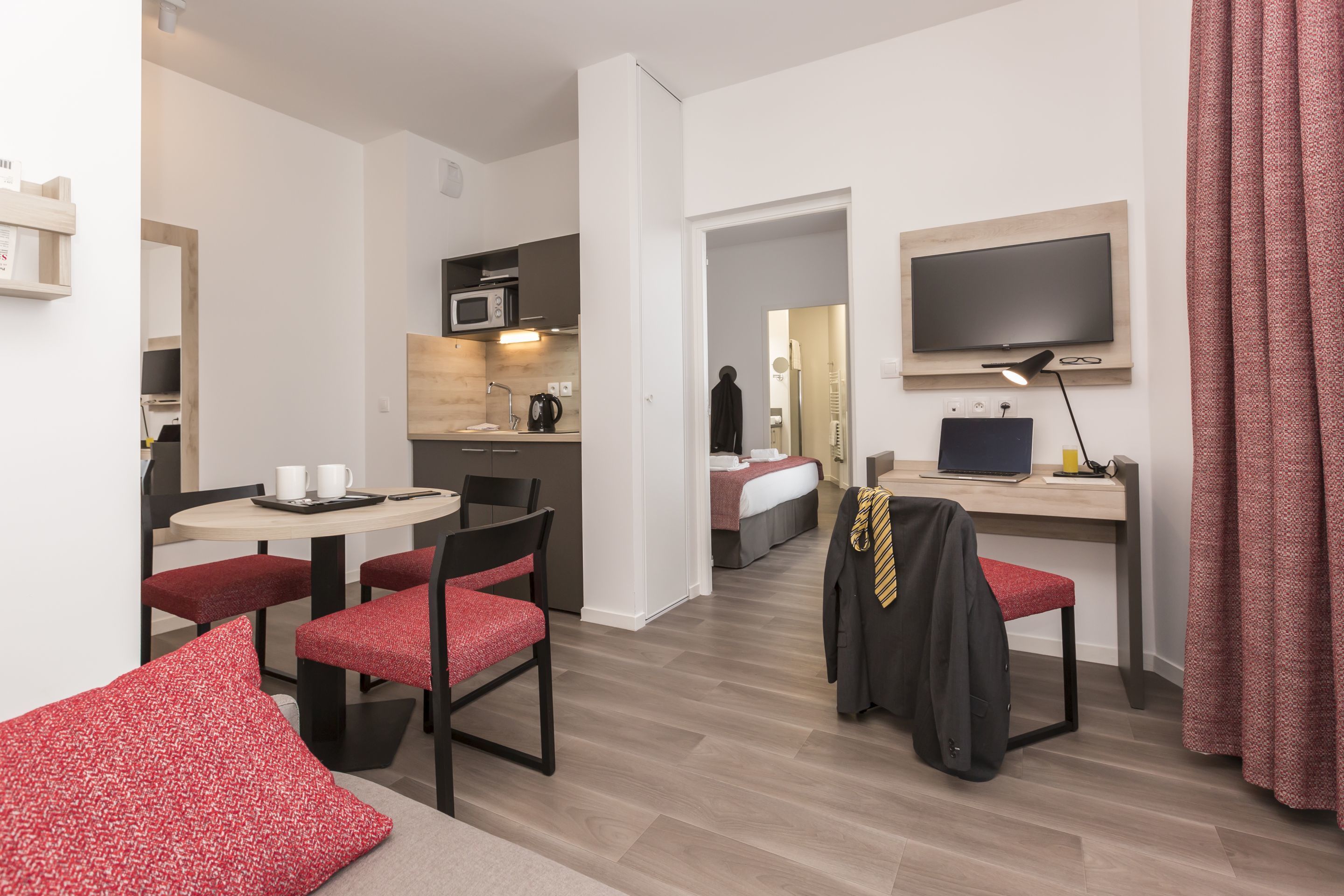 Une chambre d’hôtel équipée d’une kitchenette, d’un coin repas, d’un lit, d’une télévision et d’un bureau.