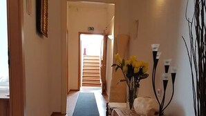 Ein Flur mit einer hölzernen Bank, einer Vase mit gelben Blumen und einer Wandleuchte.