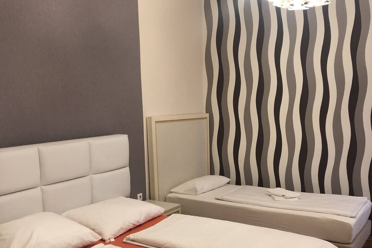 A hotel room with a bed, a nightstand, and a wall with a striped pattern.