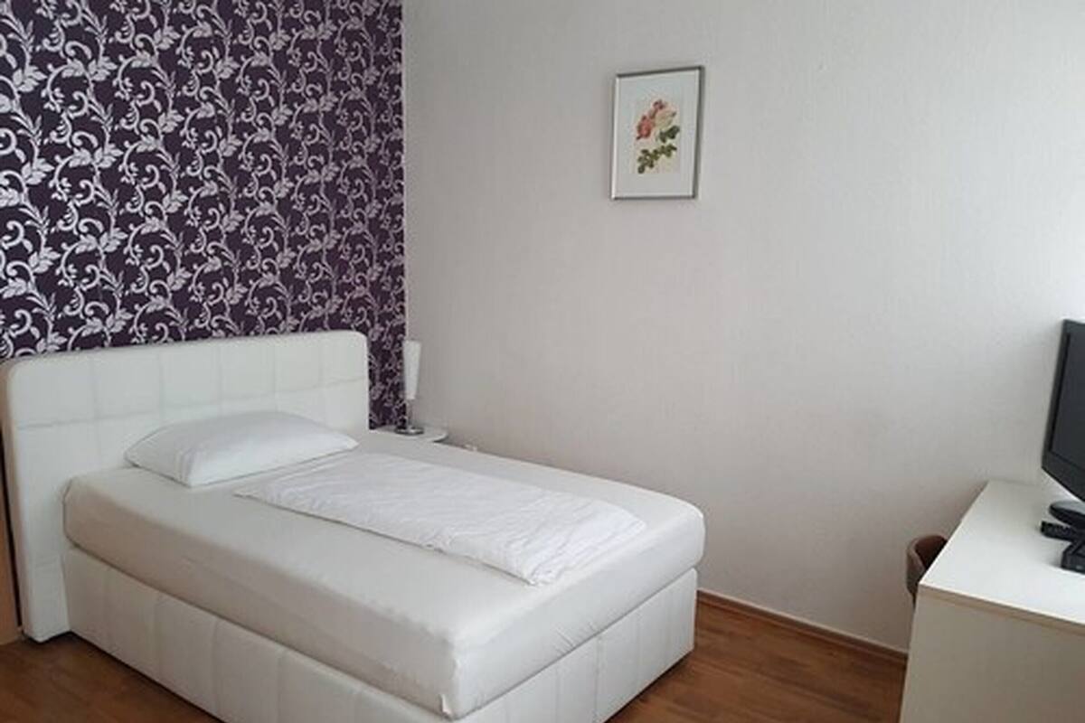 A neatly arranged bedroom with a bed, a bedside table, a lamp, and a television.