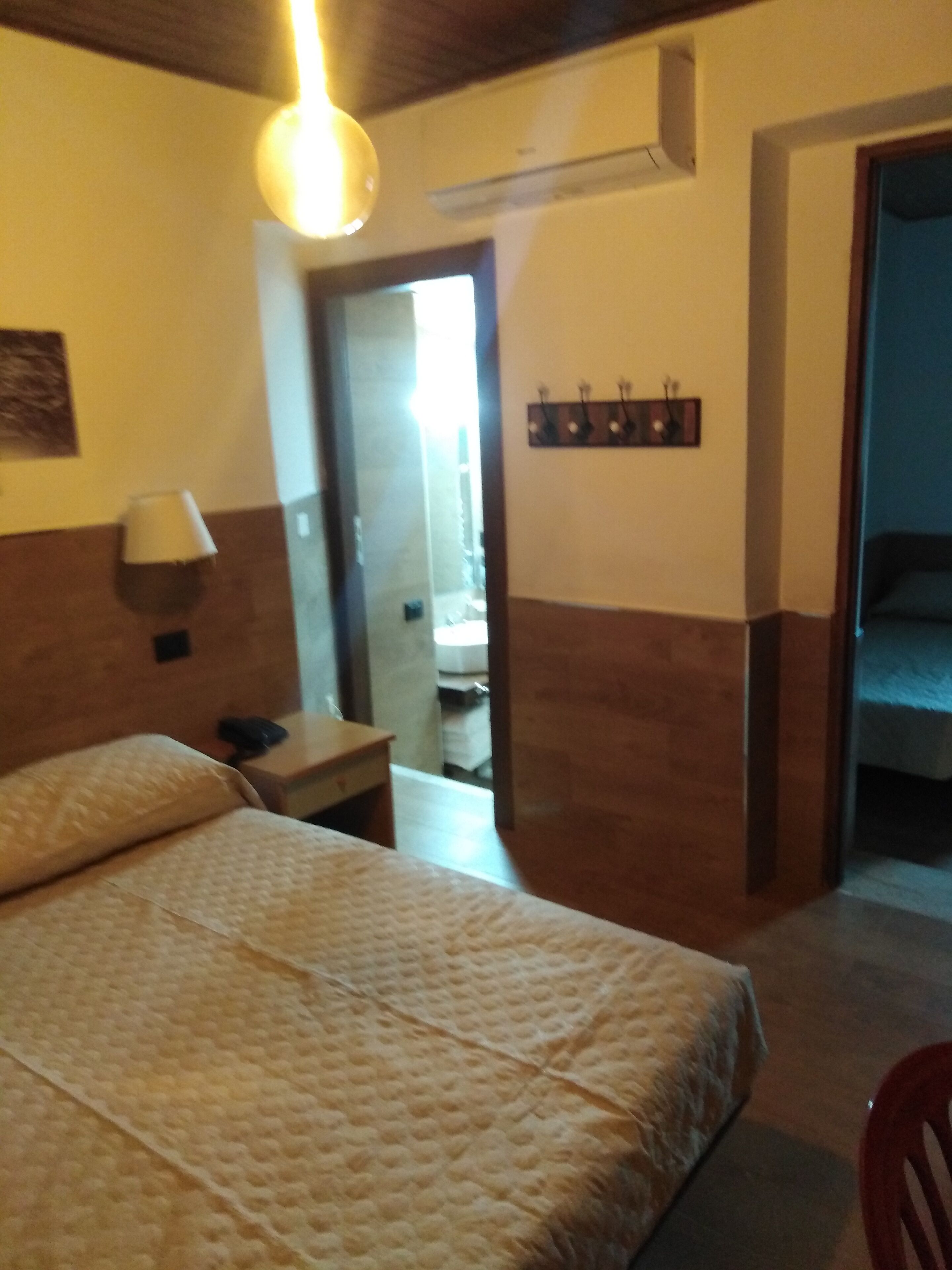 Een hotelkamer met een bed, een bureau, een lamp en een airconditioning.
