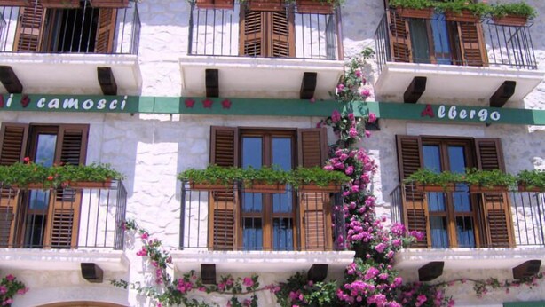 A building with multiple balconies adorned with plants and flowers. - Hotel Ai 4 Camosci (Civitella Alfedena)