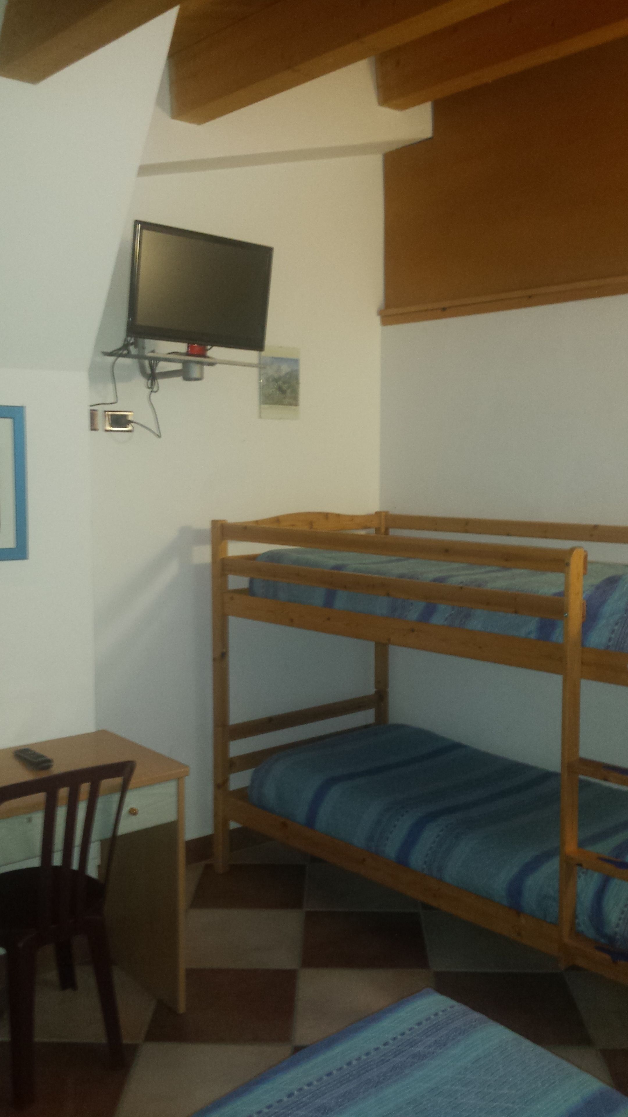 A bunk bed with a television mounted on the wall above it.