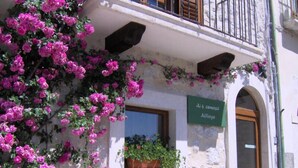 A building facade with a balcony, a window with a plant, and a sign reading "Ai 4 camisole Alergo". - Hotel Ai 4 Camosci (Civitella Alfedena)