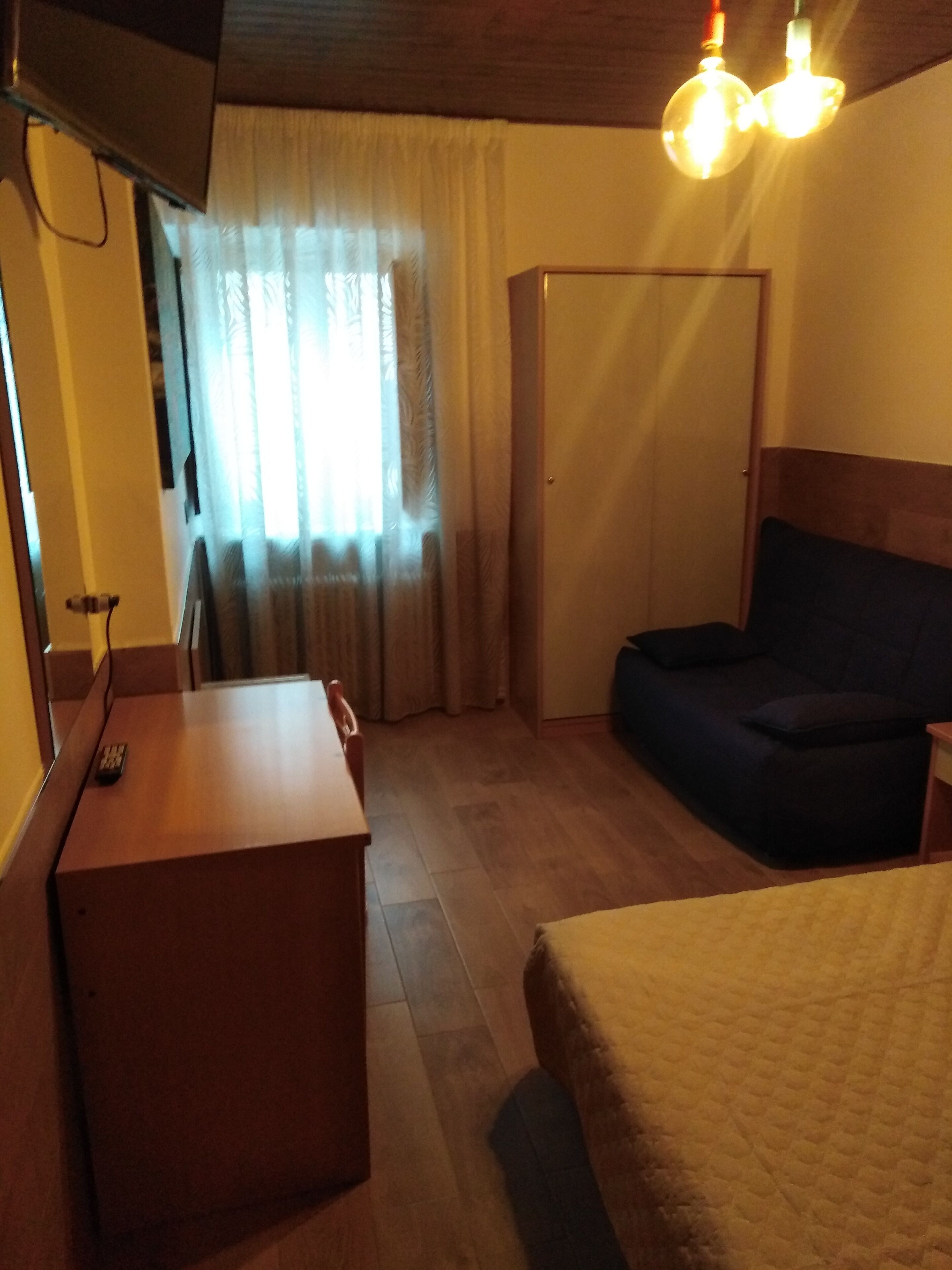 Una habitación de hotel con cama, escritorio, silla, sofá y armario.