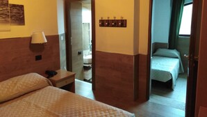 A hotel room with two beds, a bedside table with a lamp, a mirror, and a wall-mounted light fixture. - Hotel Ai 4 Camosci (Civitella Alfedena)