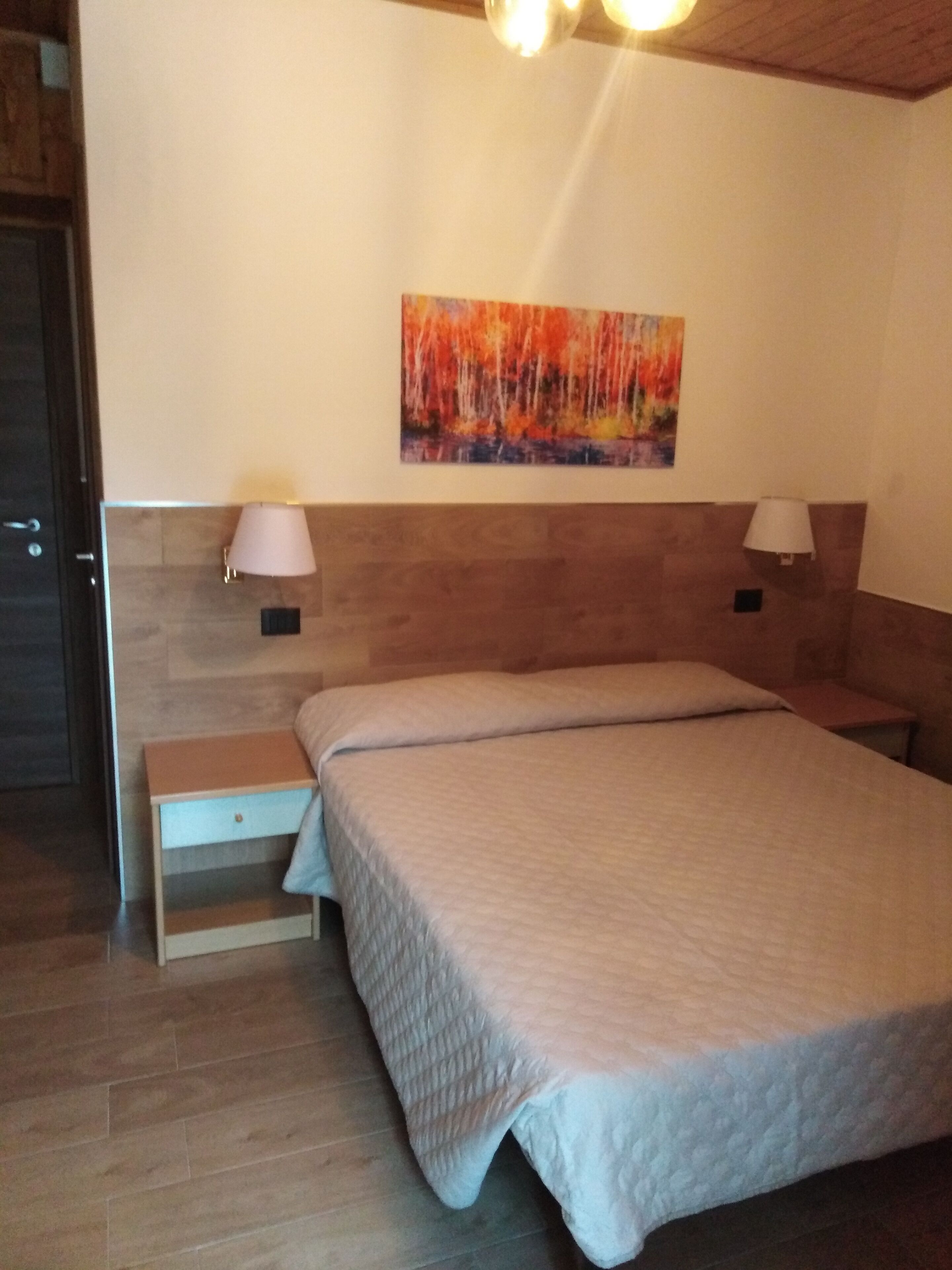 Une chambre à coucher avec un lit, des tables de chevet, un tableau au mur et un plafond en bois.
