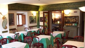 A dining area with tables covered in white tablecloths and red chairs, featuring a green ceiling and walls, and artwork on the walls. - Hotel Ai 4 Camosci (Civitella Alfedena)
