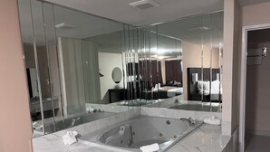 A modern bathroom with a large glass-enclosed bathtub, a large mirror, and a marble countertop.