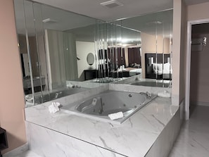 A modern bathroom with a large glass-enclosed bathtub, a large mirror, and a marble countertop.