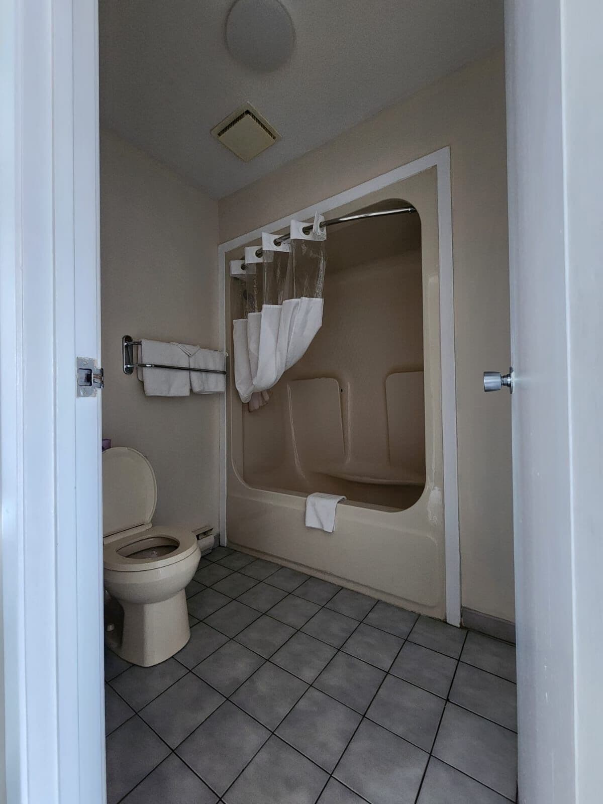 Une salle de bain équipée de toilettes, d’une baignoire et d’un rideau de douche.
