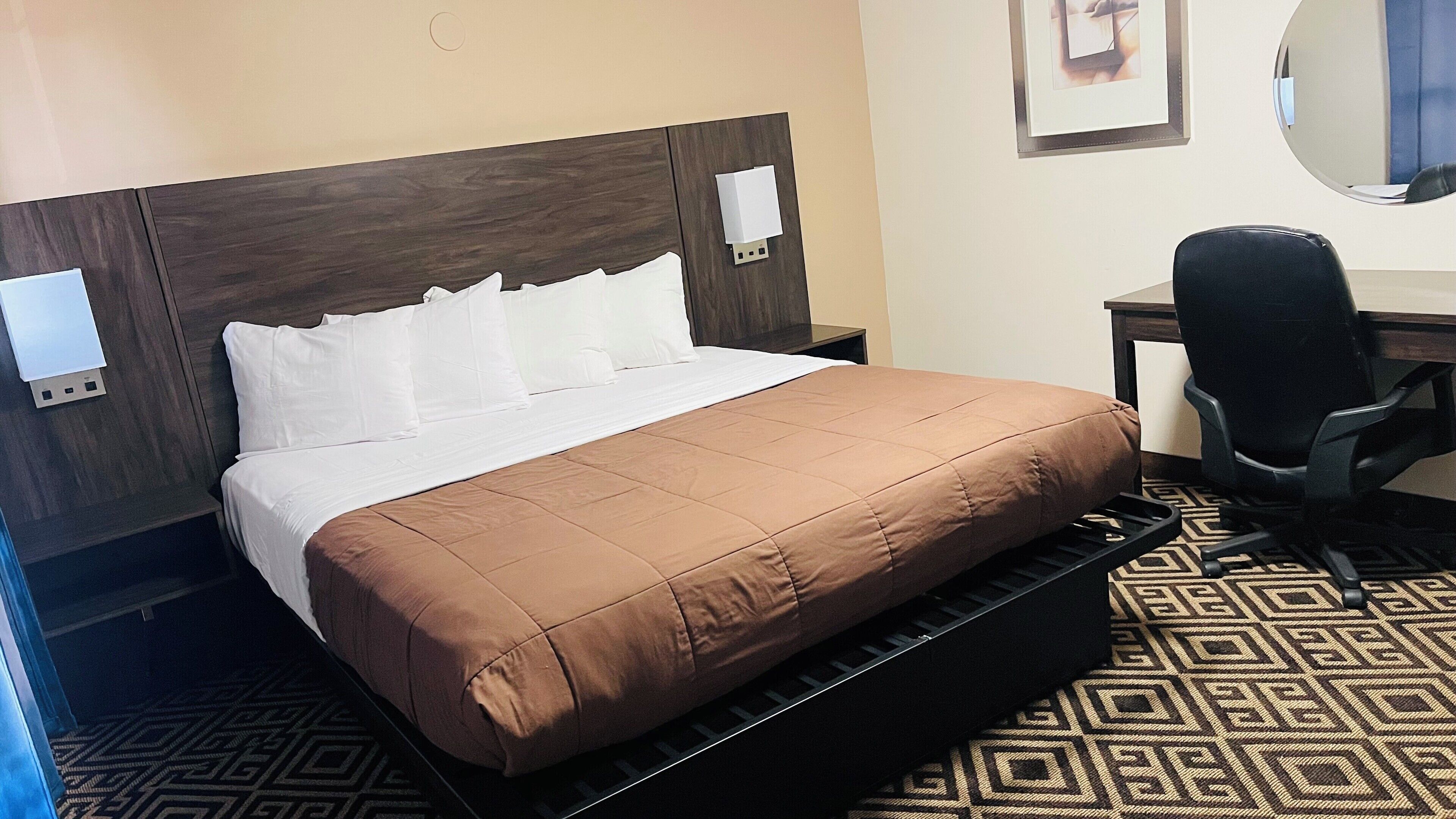 A hotel room with a bed, a desk, and a chair.