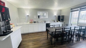 A modern kitchen with white cabinets, a coffee machine, and a breakfast bar. - Falls Lodge and Suites (Niagara Falls)