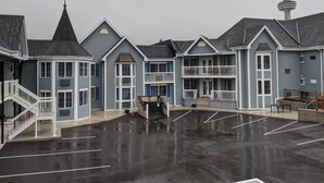 A row of blue buildings with a parking lot in front. - Falls Lodge and Suites (Niagara Falls)