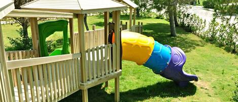 A playground with a wooden play structure and a colorful slide.