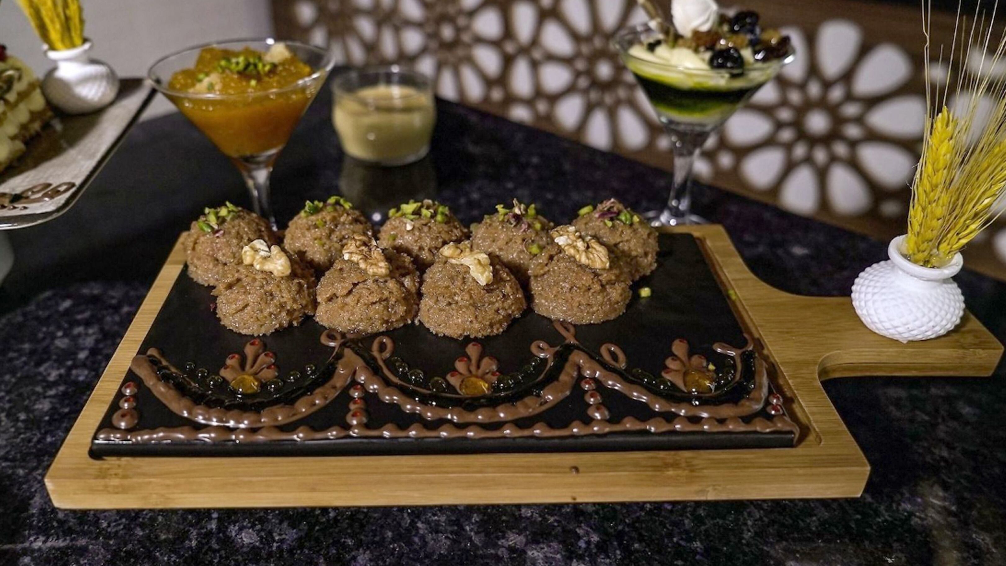 A dessert platter with sweets and a decorative chocolate design on a wooden board.