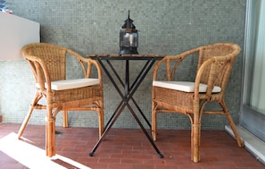 Una mesa de mimbre con dos sillas, un farol y una pared de azulejos.