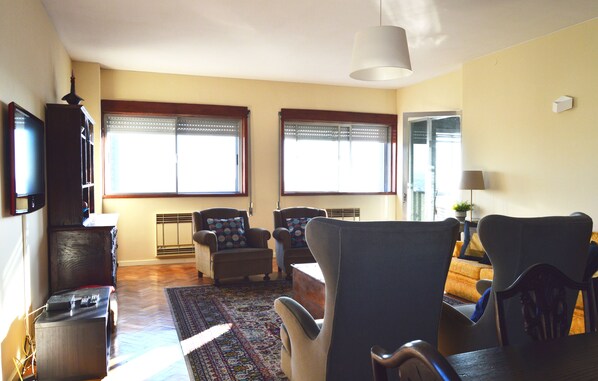 A living room with two sofas, a coffee table, a TV, and a large window with blinds.