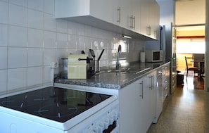 Una cocina con gabinetes blancos, una estufa, un microondas y un fregadero.