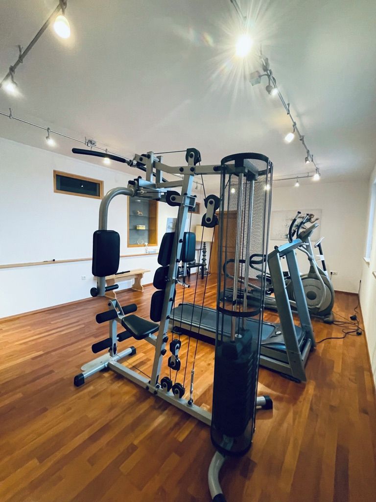 Un gimnasio con diversos equipos de ejercicio, incluyendo un rack de sentadillas, una prensa de banca y una cinta de correr.