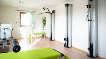 A gym with exercise equipment, a bench, and a plant.