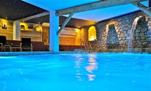 An indoor swimming pool with clear blue water, stone walls, and wooden beams. - Chambres d'Hôtes Mas La Jaïna (Bargemon)