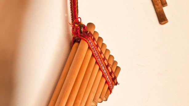 Un conjunto de instrumentos de percusión de madera, posiblemente una marimba, con un hilo rojo sujeto, frente a una pared lisa.