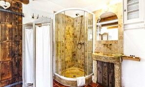 A bathroom with a glass-enclosed shower, a wooden door, and a stone sink. - Chambres d'Hôtes Mas La Jaïna (Bargemon)