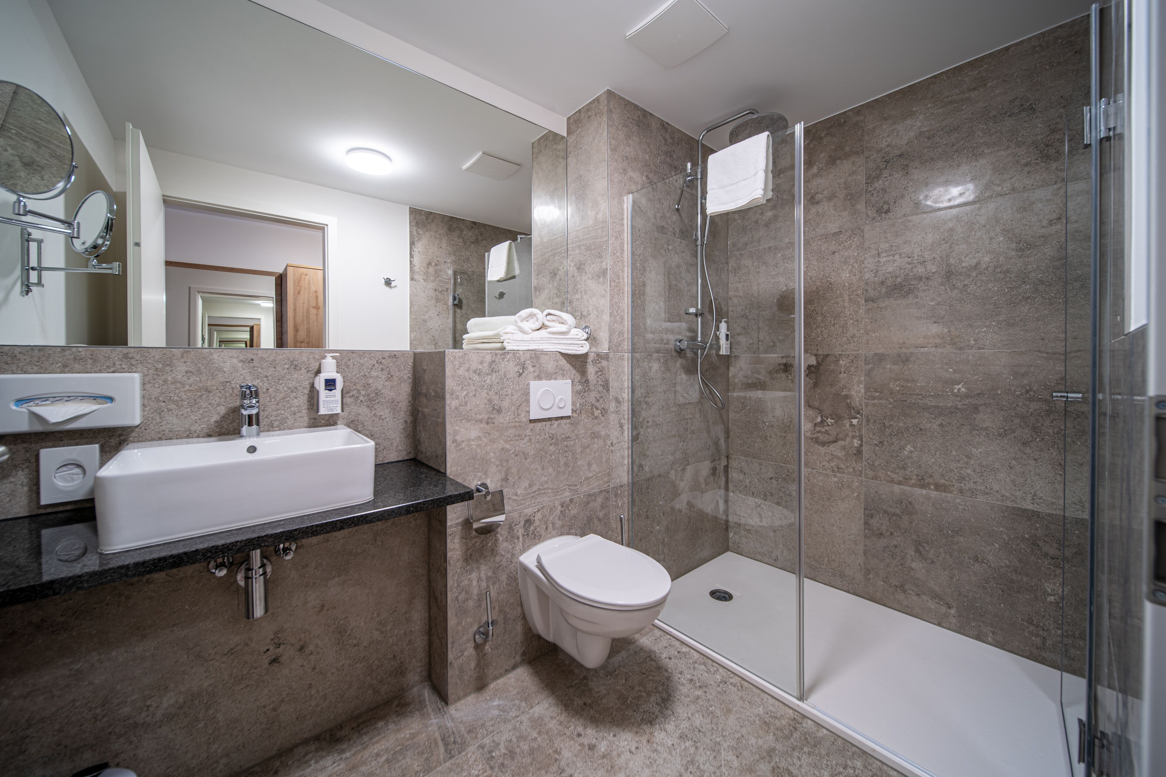 Une salle de bain moderne avec un lavabo, des toilettes et une douche à parois de verre.