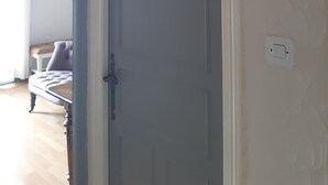 Une pièce avec une porte grise, un panneau en forme de cœur sur lequel est écrit « TOILETTES », un interrupteur blanc et un luminaire noir fixé au mur.