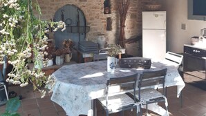 Un espace de restauration extérieur de style rustique, avec un mur en pierre, un plafond en bois et un sol carrelé.