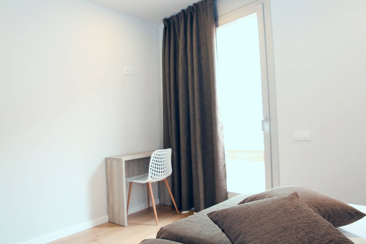 A bedroom with a bed, a desk, and a chair.